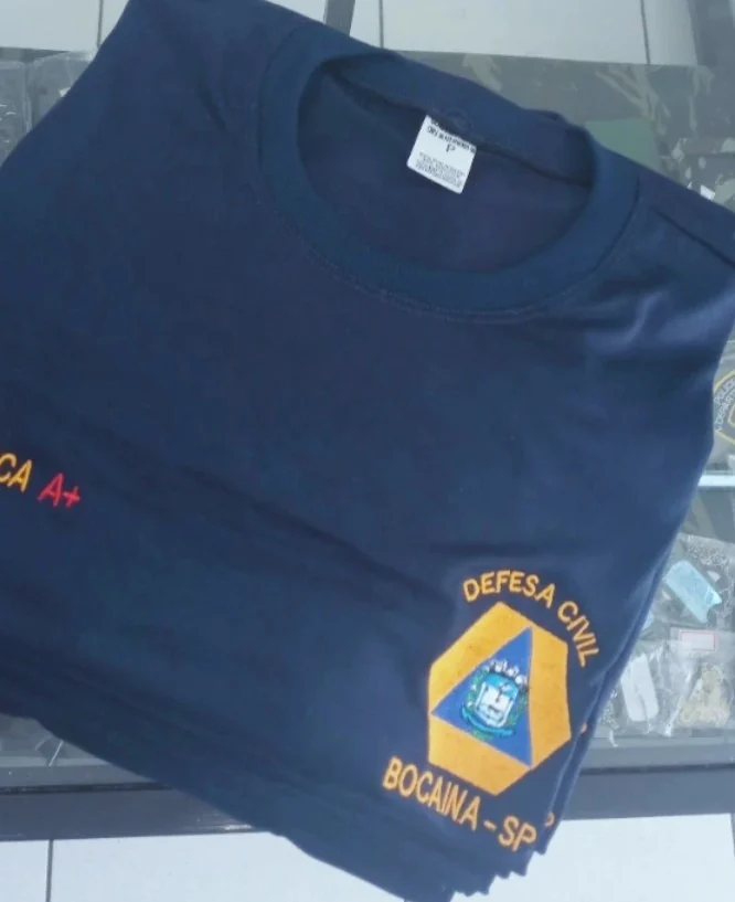 Camiseta azul com bordado de identificação e emblema de Defesa Civil
